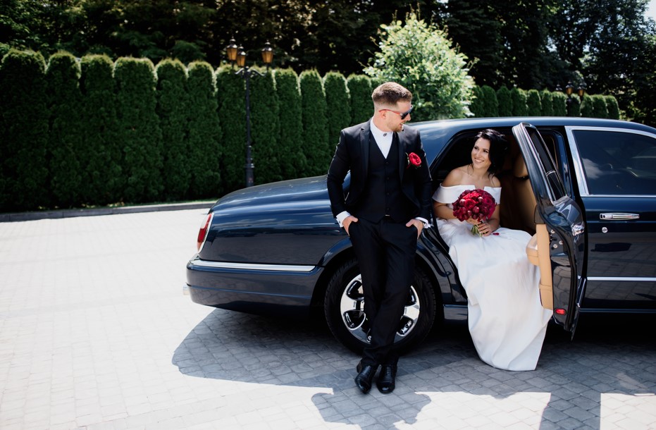 beautiful wedding couple is smiling black car