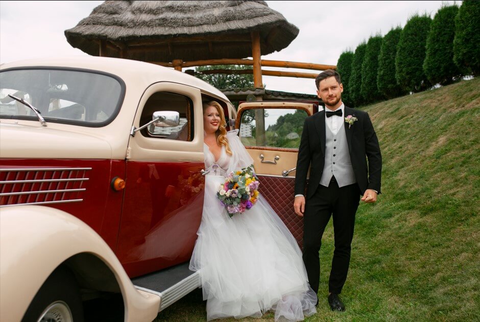 full shot couple posing with vintage car